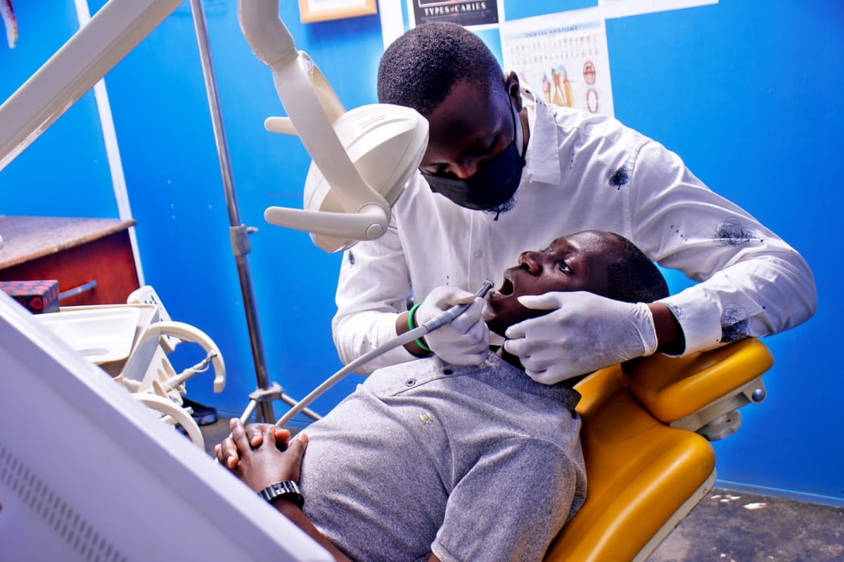 Dentist examining a young patients teeth in a dental chair with blue background
