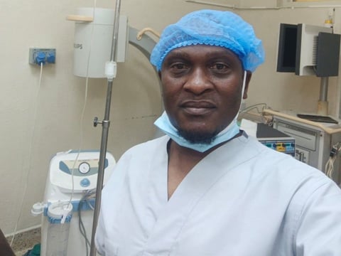 Medical professional wearing surgical cap and mask in hospital room with medical equipment in background
