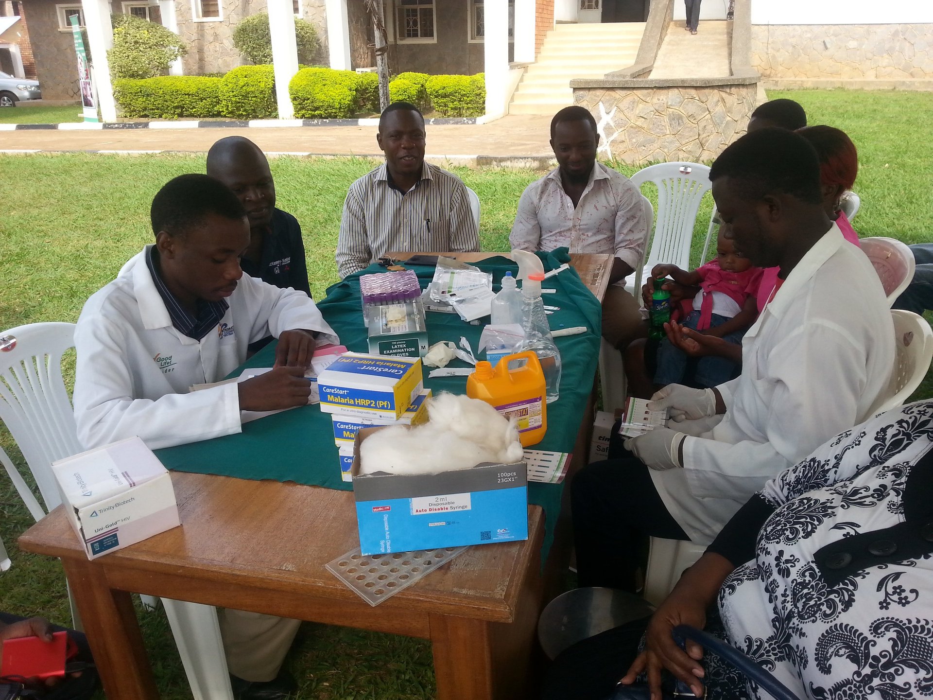 Group of people sitting around a wooden table outdoors engaged in discussion