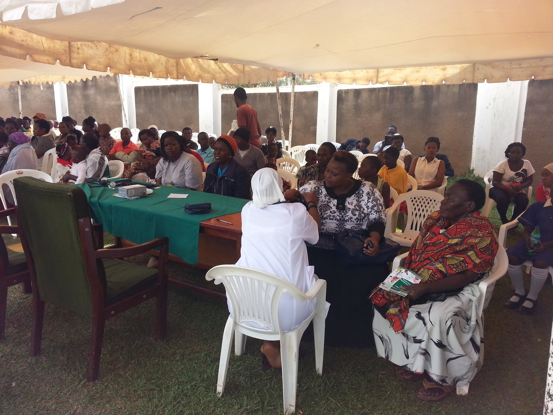 Large group of women seated in a tent during a community gathering