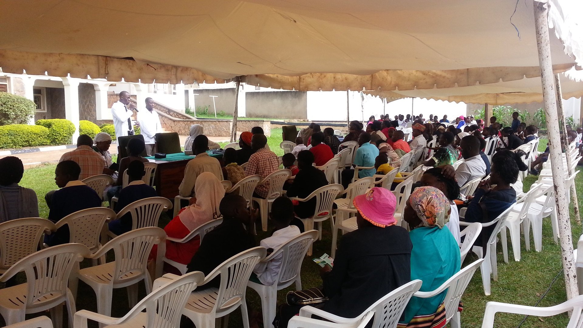 Large outdoor community gathering with diverse attendees at a healthcare event under a tent