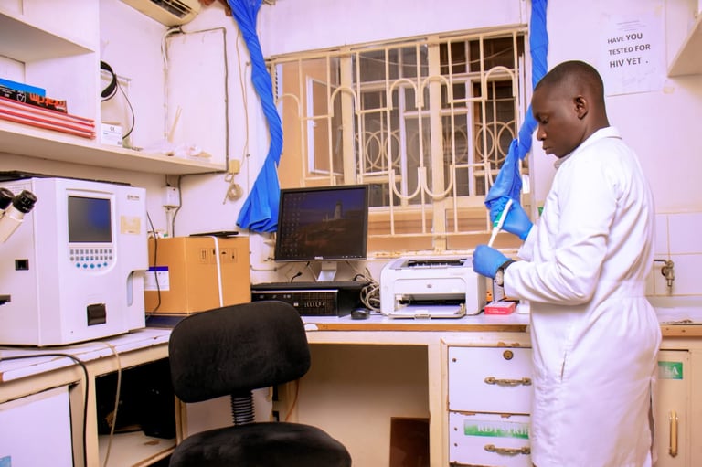 Laboratory technician in white coat working at a desk with scientific equipment and computer in a medical lab