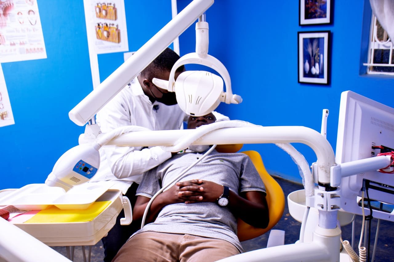 Patient receiving dental treatment in a blue dental office with overhead light and equipment