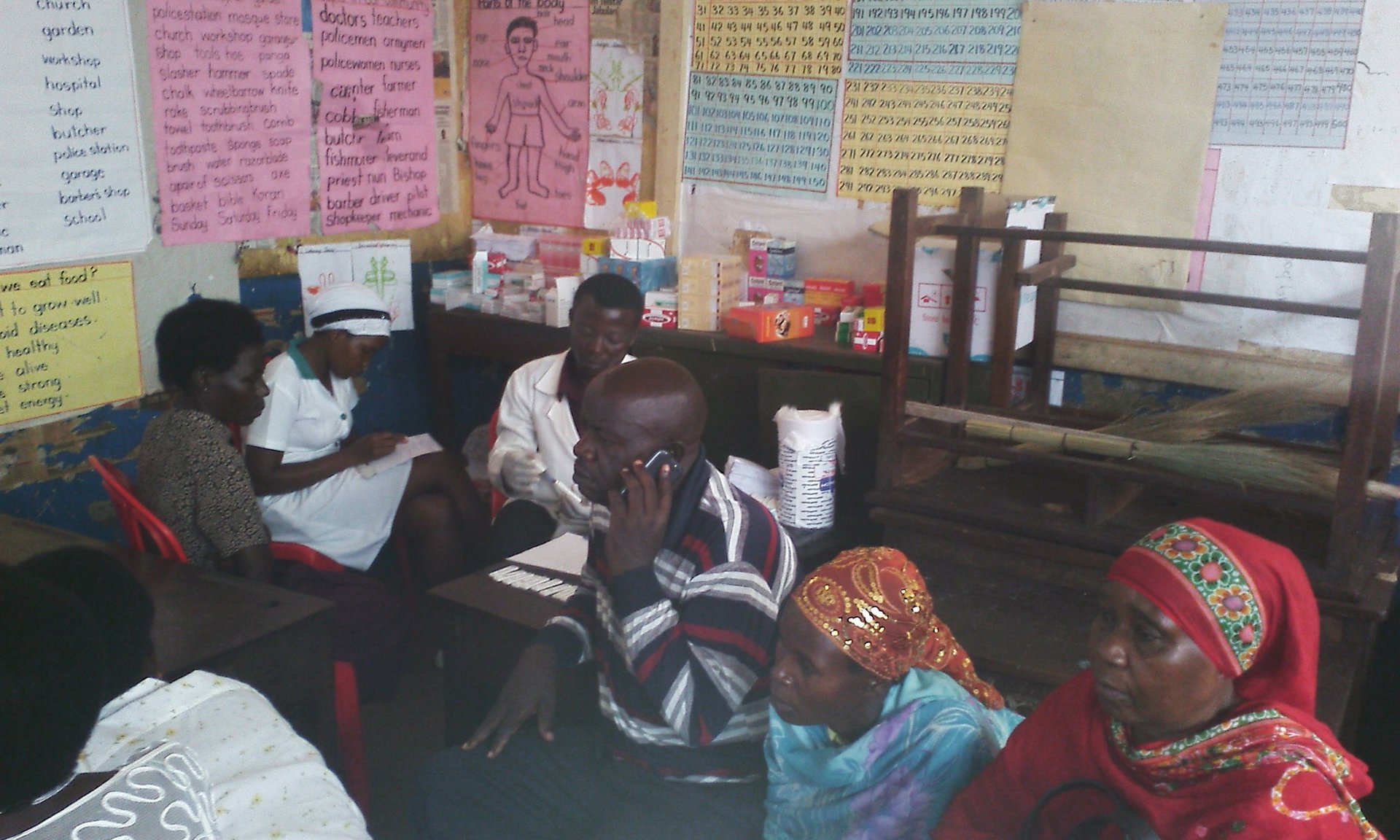 Group of women sitting on floor in classroom with colorful educational posters on walls and teaching materials around them